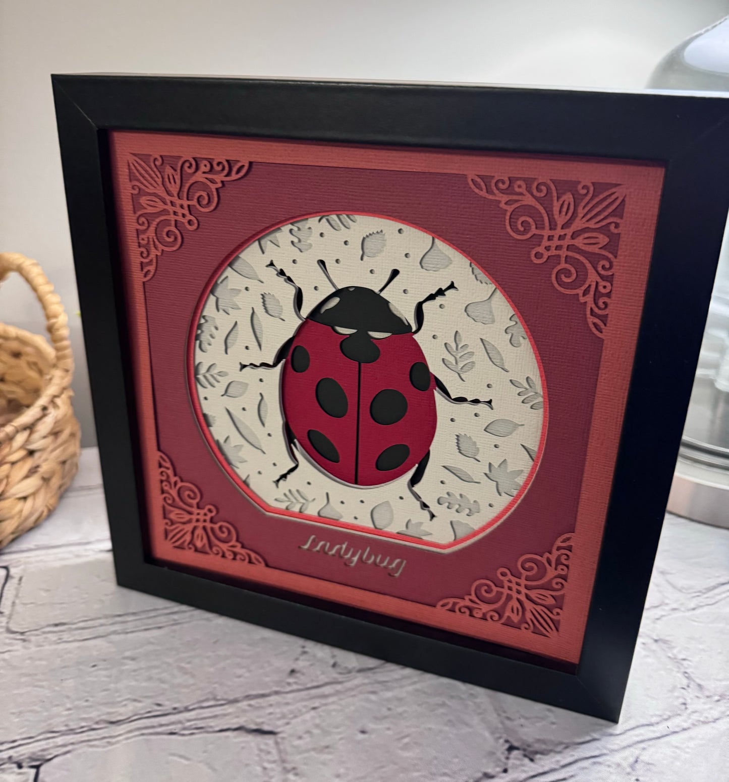 Intricate frame ladybug 3D paper art in a shadowbox